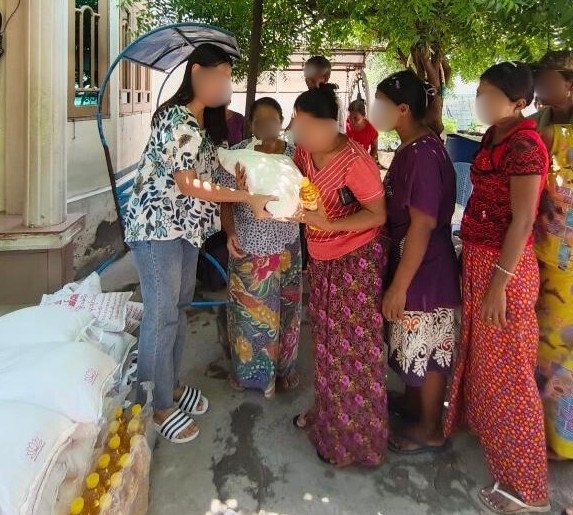 食糧を渡す現地パートナー団体スタッフと配布にならぶ人々